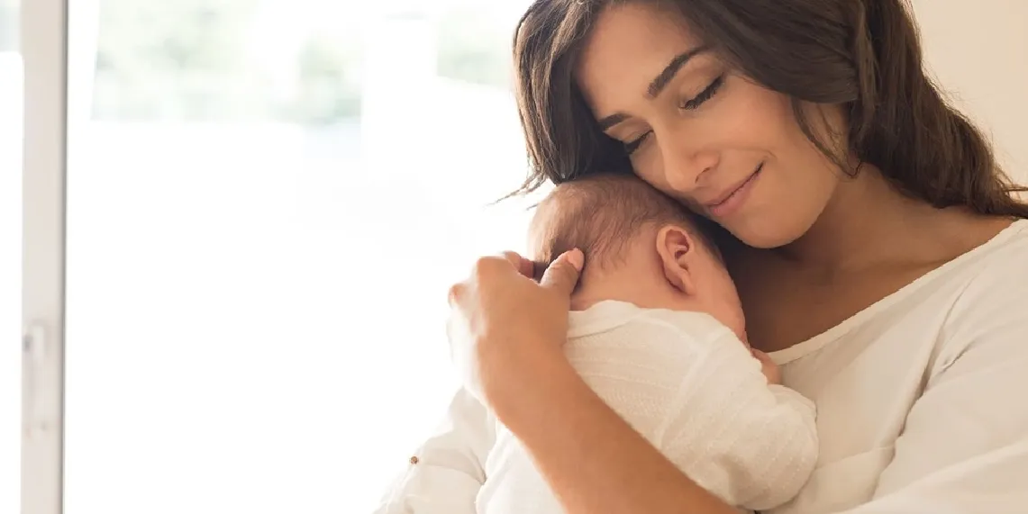 New mom holding newborn lovingly at home during early postpartum recovery
