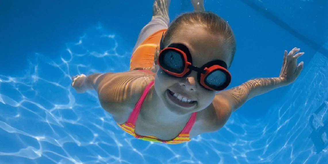 Girl swimming underwater in pool showing summer water activity that most commonly causes swimmer's ear in children