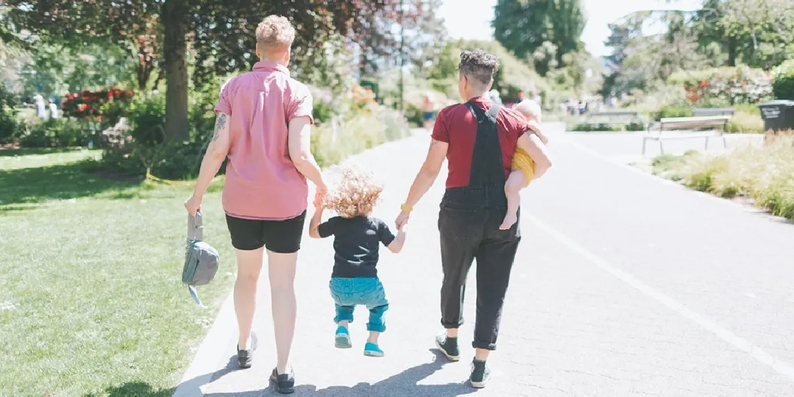 Family walking in park with two young children showing active life at twelve months postpartum