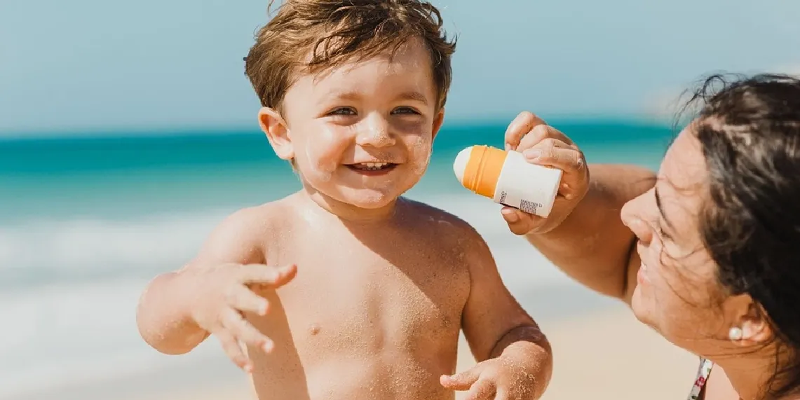 Mom applying sunscreen to child_s face building sun protection habits that reduce skin cancer risk.webp