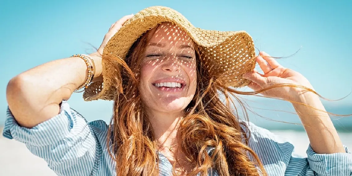Woman smiling happily in summer sunlight showing mood and serotonin benefits of healthy sun exposure.webp