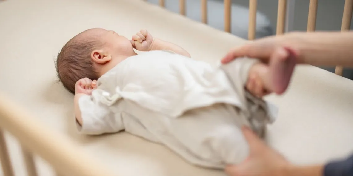 Newborn baby in crib with parent nearby showing early infant care and bowel movement monitoring