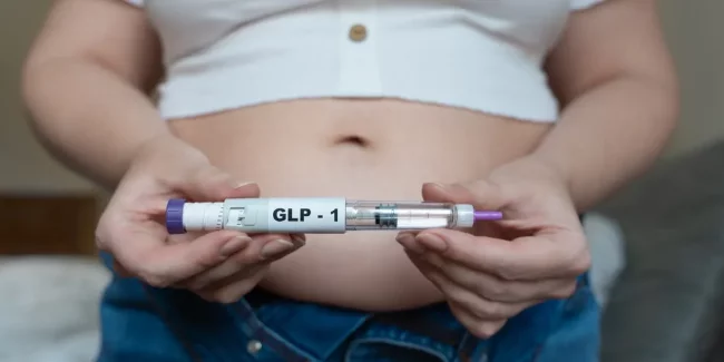 Person holding GLP-1 injection pen showing how semaglutide and tirzepatide medications are administered by injection