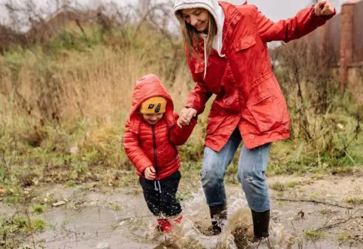 Child playing outside in spring in the rain with their mom