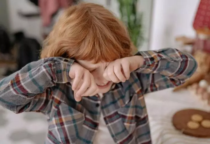 Overtired child rubbing eyes during play