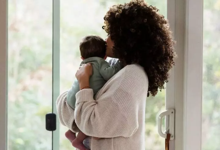 Mother holding baby near window