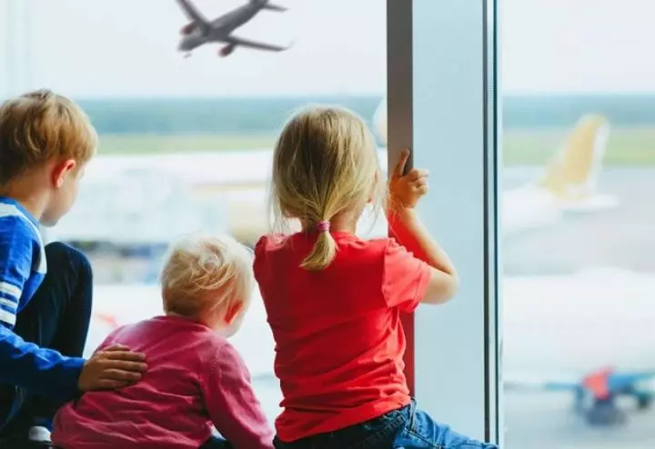 Children watching airplanes at airport window