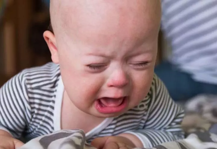 Fussy-baby-crying-during-tummy-time-with-parent-nearby-offering-comfort.jpg