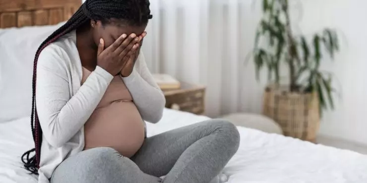 FeaturedImage-anxious-pregnant-woman-covering-face-bedroom.jpg