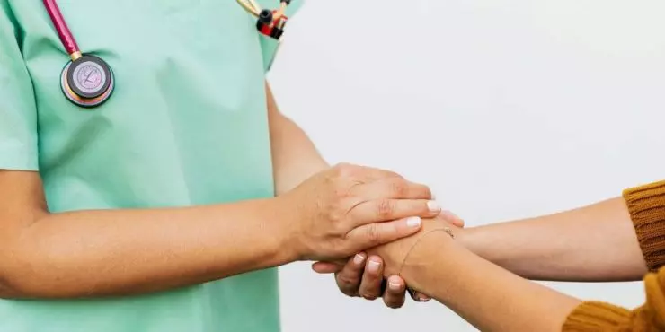 Doctor and postpartum patient gently holding hands