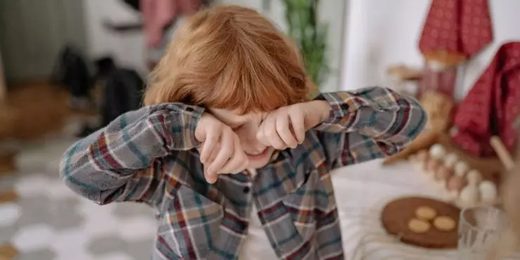 Overtired child rubbing eyes during play