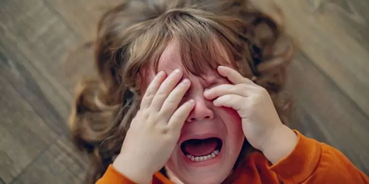 Overtired child rubbing eyes during play