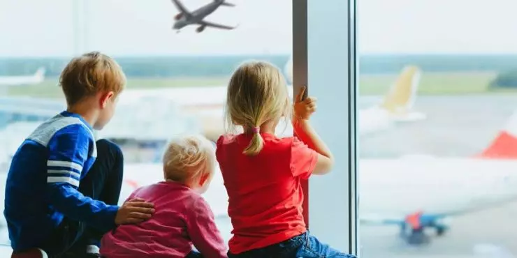 Children watching airplanes at airport window
