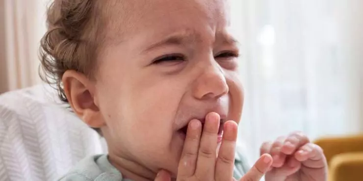 Baby-chewing-on-fingers-showing-signs-of-teething-discomfort-and-fussiness.jpg