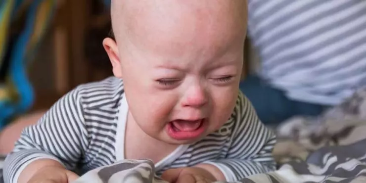 Fussy-baby-crying-during-tummy-time-with-parent-nearby-offering-comfort.jpg