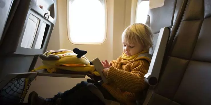 Child traveling on airplane with tablet