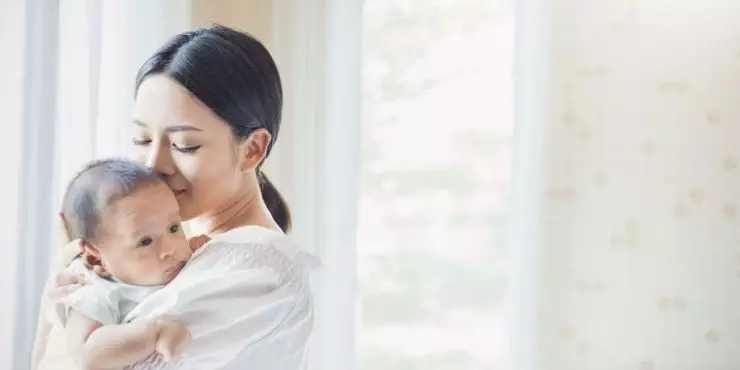 Parent holding baby near sliding glass door